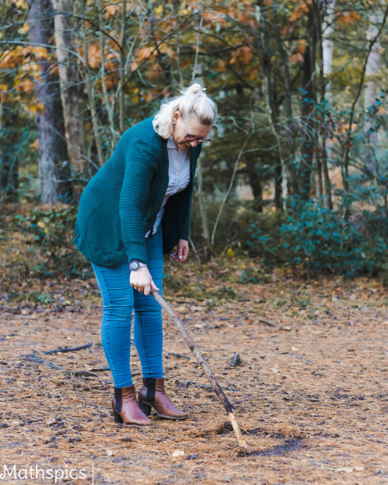 Woman drawing in the forest floor with a stick, symbolizing reflection and new beginnings for expat women in nature therapy.