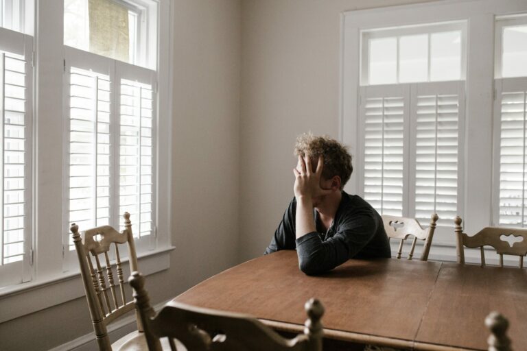 Expat sitting in a room, feeling low and withdrawn, reflecting the loneliness and seasonal sadness often faced during winter abroad.