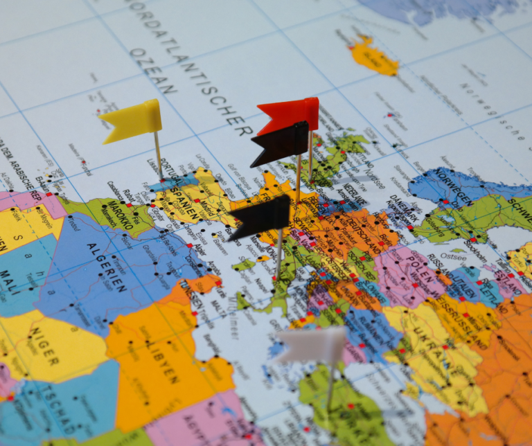 Map of Europe with colorful flags marking destinations, symbolizing the expat journey and the search for belonging.