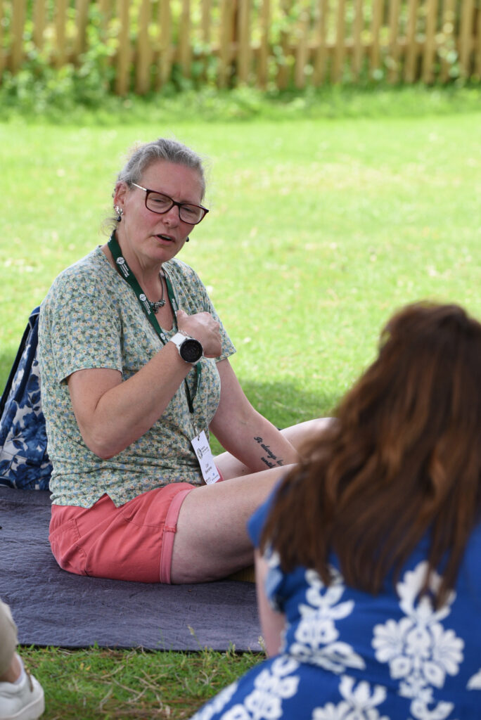 Facilitating an outdoor discussion and responding to a participant's question during a nature-based learning session.